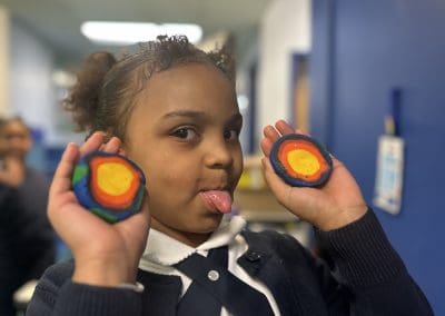A girl holds open a clay model of the earth in two hands showing the layers inside.