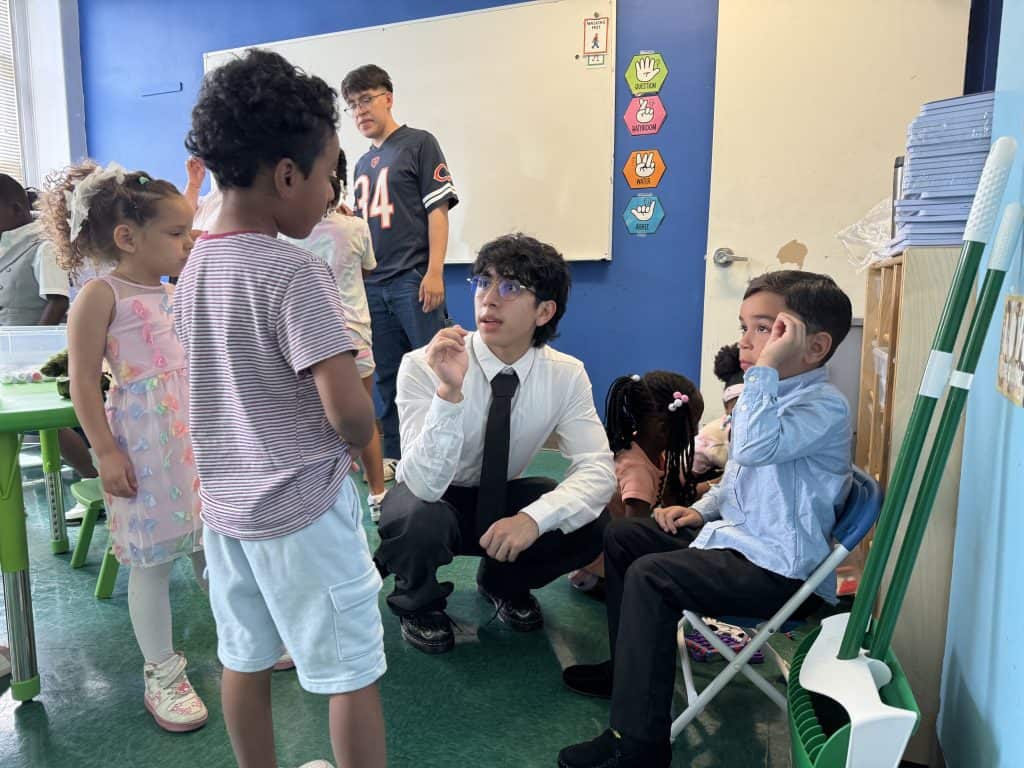 Adan Juarez Image showing Adan Juarez crouching between two students as he mediates the conflict between them.